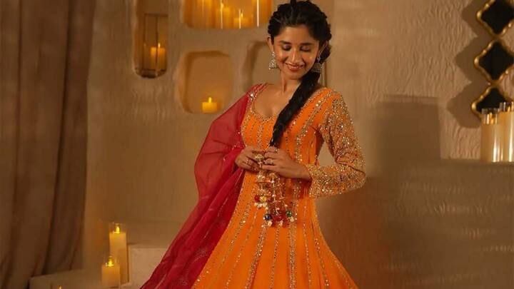 Kanika Mann dazzles in a bright orange Anarkali adorned with golden sequin and zari embroidery. The flared silhouette paired with a contrasting deep pink dupatta adds regal allure, perfect for newlywed brides celebrating their first Karwa Chauth. (Image Source: Instagram/ bboutique_ig)