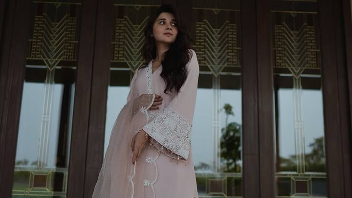 In this baby pink suit, Kanika exudes regal charm with a modern twist. The flared sleeves, embroidered short kurta, sheer thread-work dupatta, and matching palazzo pants make it an ideal choice for a graceful and light festive look. (Image Source: Instagram/ officialkanikamann)