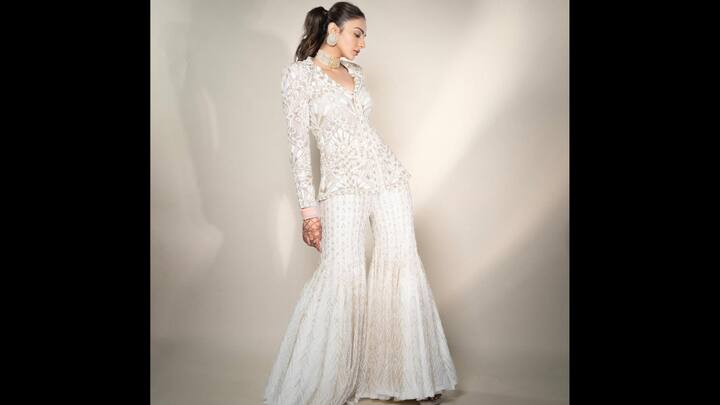 6. Glamorous Ivory Coast-Ord Set: Rakul Preet Singh exudes modern chic in this ivory embroidered co-ord set which redefined festive fashion with a fusion of glamour and tradition. The outfit features a structured full-sleeve embellished blouse paired with flared sharara pants, both adorned with delicate beadwork and geometric embroidery. The monochrome palette enhances the sophistication of the look while the intricate patterns add a couture edge. Rakul styled it with statement jewellery including a choker, oversized studs, and her chooda bangles. (Image Source: Instagram/@rakulpreet)