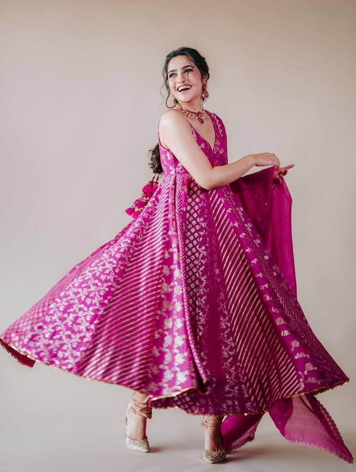 इस लुक में रुक्मिणी ने ट्रेडिशनल अंदाज़ में एक शानदार फ्यूशिया पिंक बनारसी अनारकली सूट पहना है, जिसमें सिल्वर ज़री वर्क बेहद खूबसूरत लग रहा है. उन्होंने इसे मैचिंग दुपट्टे, ट्रेडिशनल ज्वेलरी और हाई हील्स के साथ स्टाइल किया है.