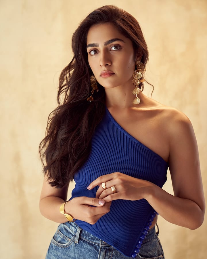 इस लुक में रुक्मिणी वसंत बेहद एलिगेंट और सटल दिख रही हैं. उन्होंने वन-शोल्डर रॉयल ब्लू टॉप पहना है जो उनके पूरे लुक को स्टाइलिश टच दे रहा है. इसके साथ उन्होंने गोल्डन स्टेटमेंट ईयररिंग्स, ब्रैसलेट और रिंग्स कैरी की हैं, जो लुक में हल्की ग्लैम का फील ला रहे हैं. ओपन वेवी हेयर और नैचुरल मेकअप उनके लुक को और भी ग्रेसफुल और क्लासी बना रहे हैं.