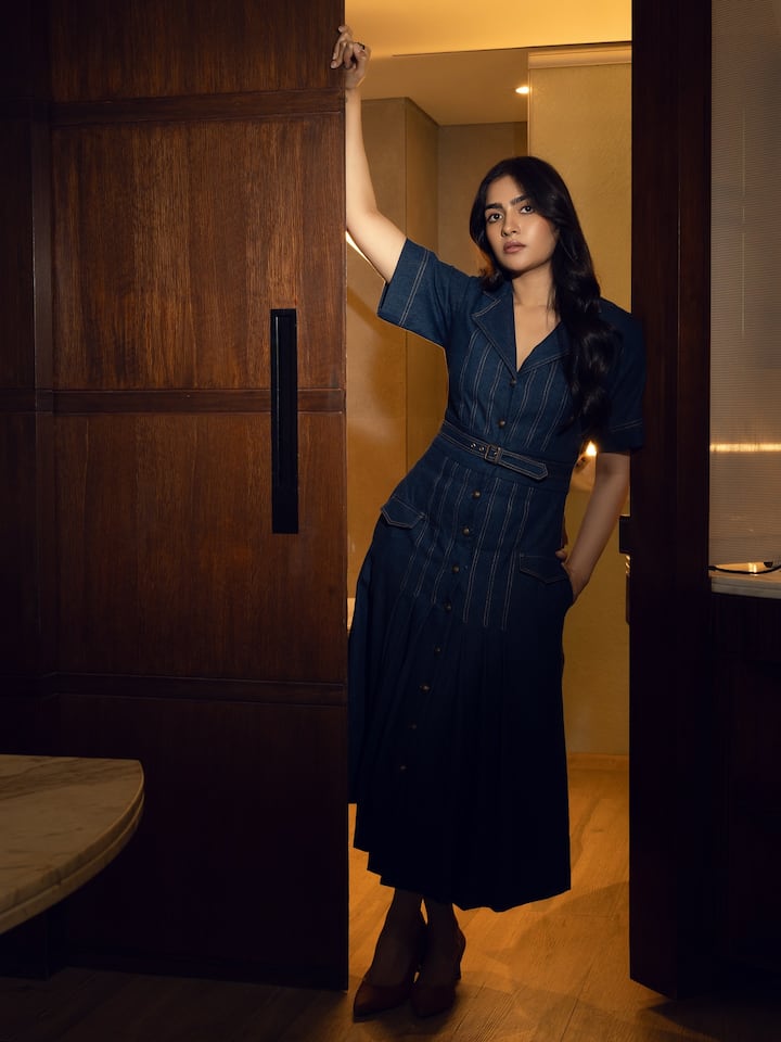 इस लुक में रुक्मिणी का अंदाज़ काफी मॉडर्न है. उन्होंने डेनिम शर्ट ड्रेस पहनी है जिसमें बेल्ट डिटेल और बटन डिज़ाइन है, जो लुक को स्ट्रक्चर्ड और स्टाइलिश बना रहा है. सॉफ्ट वेवी ओपन हेयर और न्यूड मेकअप के साथ उन्होंने इसे सिंपल लेकिन क्लासी रखा है. ब्राउन हील्स पूरे आउटफिट को कम्प्लीट कर रहा हैं. यह लुक एकदम कॉन्फिडेंट और मिनिमल चार्म से भरा हुआ है.