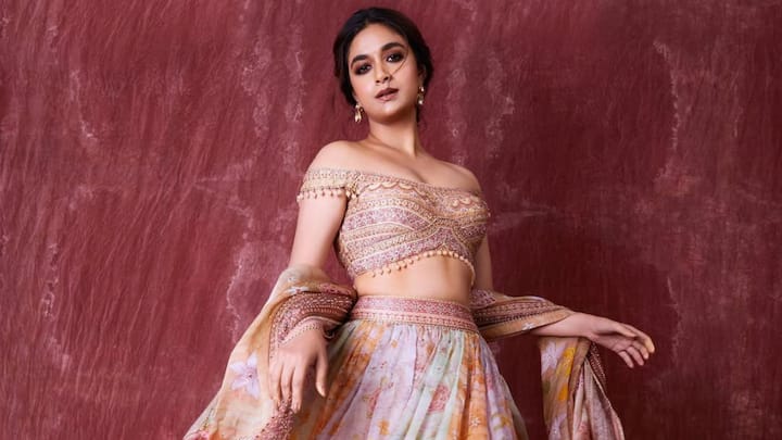 8. Ethereal Off-Shoulder Embroidered Blouse: Keerthy Suresh continues to deliver major fashion moments, and this time, she takes our breath away in a regal off-shoulder lehenga blouse that oozes elegance and artistic craftsmanship. Perfect for the upcoming wedding season or grand festive soirées, her intricately designed blouse is the ultimate inspiration for anyone seeking modern ethnic fashion with a royal twist. This stunning look features a heavily embellished blouse with off-the-shoulder sleeves, enhanced by dainty pom-pom lace trims that accentuate the neckline and hemline. The intricate threadwork, mirror embellishments, and geometric patterns create a visual masterpiece that blends traditional embroidery with a contemporary silhouette. (Image Source: Instagram/@keerthysureshofficial)