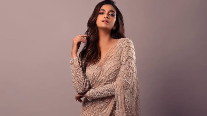 4. Sequin-Encrusted Full-Sleeve Blouse: Keerthy’s blouse is a masterclass in festive glamour. The design features a full-sleeve blouse richly adorned with intricate sequin and beadwork. The embellishments are arranged in elegant, symmetrical patterns that give it a regal and high-fashion appeal. The base colour is a soft champagne beige, allowing the shimmering silver detailing to shine without overpowering the overall look. It’s subtle, yet striking, perfect for evening receptions, Diwali parties, or sangeet nights. (Image Source: Instagram/@keerthysureshofficial)
