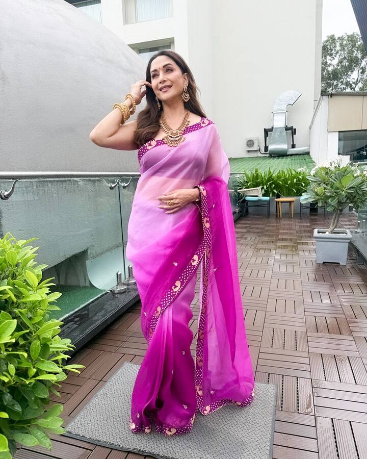 In this look, Madhuri is wearing pink and magenta shade chiffon saree. This look is perfect for an afternoon Bhai Dooj function. The saree has ombre effects and small, golden booti work on the edges giving it a beautiful and subtle festive touch. She paired her look with heavy golden jewelery like temple necklace and lots of bangles, giving a rich look to the light colored saree. If you want a mix of traditional heavy jewelery with light fabric on Bhai Dooj, then this look is great.