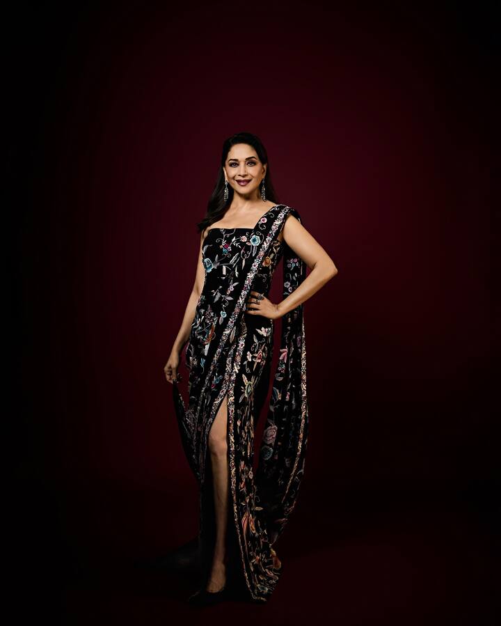Madhuri is looking very stylish and gorgeous in this black floral saree. The embroidery and prints on the saree are giving it a festive look. The high-slit design of the saree is giving it a western touch like a gown. She accessorized her look with simple diamond earrings, drawing all the attention to the saree. If you want to add modern drama with colors like black on Bhai Dooj, then you can choose this printed slit saree or this type of Indo-Western outfit.