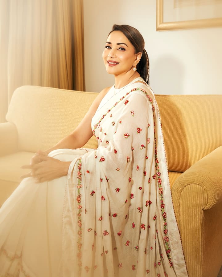 Madhuri is looking very graceful in this off-white colored saree. This look is perfect for those who want to wear subtle colors on Bhai Dooj. The fine floral embroidery done on red and green threads on the saree is giving it a festive and lovely touch. She has kept the blouse sleeveless and kept her look minimal with simple earrings and a small bindi. This look shows how beautiful you can look even without much glitter.