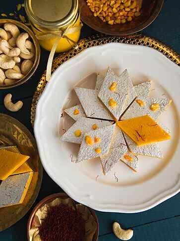 पाक तयार झाला की गॅस मंद करावा आणि त्यात काजू पावडर घालून नीट मिसळावी.