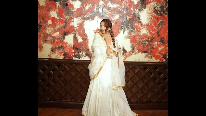 6. ईथर एथनिक पोशाक: गोल्डन डिटेलिंग के साथ इस शाही हाथी दांत के पहनावे में मलायका अरोड़ा दिव्य आकर्षण का अनुभव करती हैं, जो उत्सव की परिपूर्ण चमक बिखेरती है। सोने की धार वाले नाजुक दुपट्टे के साथ बहता हुआ सिल्हूट, संयमित विलासिता का सार दर्शाता है। गहरी नेकलाइन और जटिल अलंकरण उसके अन्यथा क्लासिक पारंपरिक लुक में एक आधुनिक स्वभाव जोड़ते हैं। चिकनी चोटी, स्टेटमेंट चोकर और भारी झुमके के साथ स्टाइल किया गया, मलायका का पहनावा लालित्य का दर्शन कराता है। यह लुक भव्य समारोहों, शादी के उत्सवों या किसी भी उत्सव के अवसर के लिए आदर्श है जहां अनुग्रह ग्लैमर से मिलता है। (छवि स्रोत: इंस्टाग्राम/@मालाइकारोराऑफिशियल)