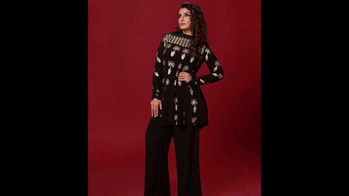7. Black And Gold Ensemble: Raveena Tandon wore a chic black and gold ethnic co-ord set that perfectly blends regal charm with modern elegance. The outfit features a black long-line kurta adorned with gold paisley motifs and intricate embroidered detailing around the neckline. The high-neck silhouette adds a sophisticated edge, while the flared hem gives it a flattering, contemporary twist. The ornate golden accents stand out beautifully against the inky black base, giving the outfit a rich, festive vibe without going over the top. The gold detailing keeps it traditional, while the silhouette makes it contemporary. (Image Source: Instagram/@officialraveenatandon)