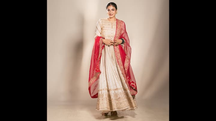 5. Ethereal In Ivory And Red Anarkali Ensemble: Raveena Tandon channels divine elegance in this ivory and red Anarkali suit that exudes royal sophistication. The ivory base, richly embroidered with golden threadwork, lends a timeless charm, while the vibrant red dupatta bordered with intricate zari detailing adds a regal contrast. The voluminous flare and luxurious fabric make this look ideal for grand festive occasions and winter weddings. This outfit perfectly balances traditional opulence with modern femininity, making it a must-save inspiration for the festive wardrobe. (Image Source: Instagram/@officialraveenatandon)