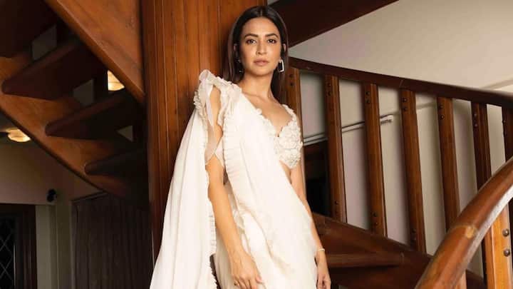 द ड्रीमी व्हाइट रफ़ल साड़ी: कृति का ईथर रफ़ल साड़ी लुक सफ़ेद रंग में एक दर्शन है। कढ़ाईदार स्वीटहार्ट-नेकलाइन ब्लाउज के साथ कैस्केडिंग रफल्स एक नरम, रोमांटिक सिल्हूट बनाते हैं। उसकी चमकती त्वचा और आकर्षक झुमके दिन के जश्न या शादी के ब्रंच के लिए सही मात्रा में उत्सव का आकर्षण जोड़ते हैं। (छवि स्रोत: इंस्टाग्राम/ कृति.खरबंदा)