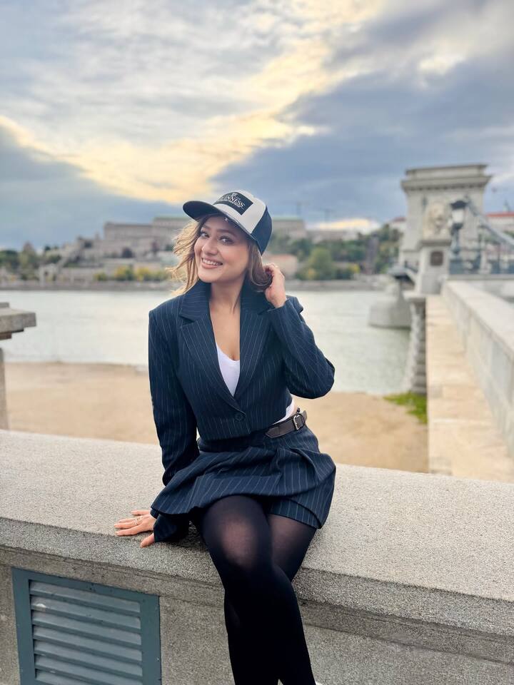 मदालसा इस तस्वीर में एक नेवी ब्लू पिनस्ट्राइप को-ऑर्ड सेट पहने हुई हैं. इस सेट में एक क्रॉप जैकेट और मैचिंग मिनी स्कर्ट शामिल है. उन्होंने अंदर एक सफ़ेद टॉप पहना है और नीचे काले रंग की टाइट्स पहनी हैं, जिससे उनका यह लुक फ़ॉर्मल और ट्रेंडी का अच्छा मिक्स लग रहा है. एक्सेसरीज में, उन्होंने अपनी कमर पर एक पतली ब्राउन बेल्ट बांधी है और सिर पर काले और सफेद रंग की कैप लगाई है. यह लुक कैज़ुअल, स्पोर्टी और चिक का एक बेहतरीन कॉम्बिनेशन है.