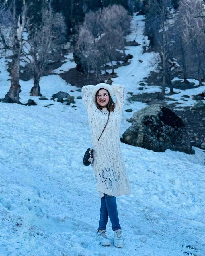 यहां मदालसा ने बर्फ वाले माहौल के लिए सफेद रंग का वुलन स्वेटर ड्रेस पहना है. इसके साथ नीली जींस और सफेद जूते पहने हैं. उन्होंने सिर पर वुलन टोपी लगाई है और एक छोटी काली बैग भी ली है. बाल खुले हैं और मेकअप नैचुरल है.