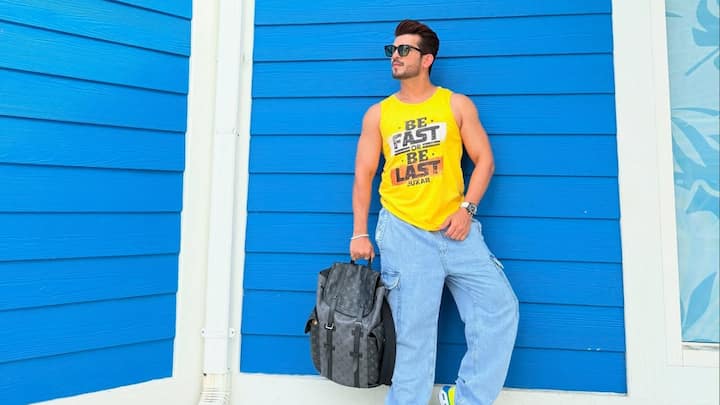 Bold and sporty, Arjun wears this bright yellow tank with baggy blue cargos and neon-detailed sneakers. The look channels youthful energy, perfect for a gym-to-street transition. (Image Source: Instagram/ arjunbijlani)