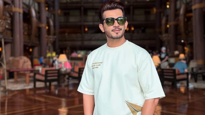 Arjun rocks this minimal co-ord set featuring an oversized cream tee with playful patch detailing and matching shorts. Styled with black sunglasses and a silver watch, the outfit is easy, modern, and travel-ready. (Image Source: Instagram/ arjunbijlani)