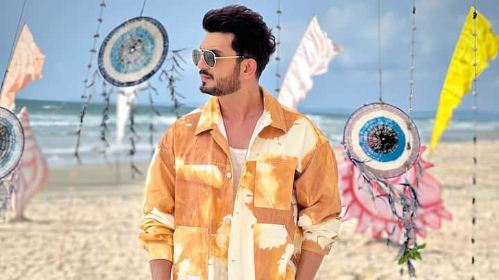 Sporting earthy tones, Arjun pairs this tan tie-dye overshirt with off-white cropped pants for a smart-casual vibe. With white sneakers and aviator shades, the look blends modern style with relaxed sophistication. (Image Source: Instagram/ arjunbijlani)