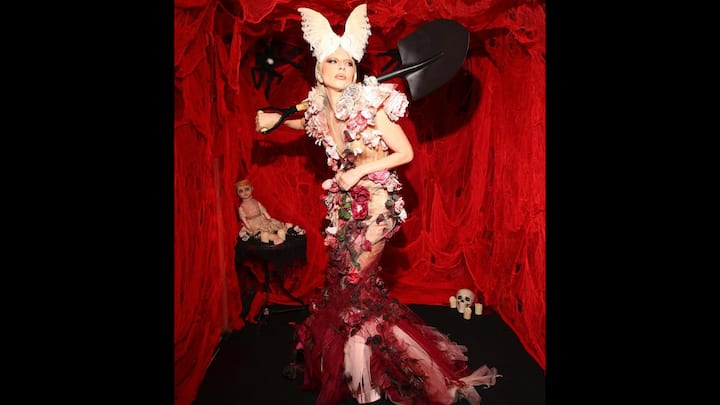 6. लेडी गागा: ग्रैमी विजेता आइकन ने द गार्डन ऑफ ईडन एंड इट्स गार्डेनर को मूर्त रूप दिया, जो उनके नवीनतम एल्बम से प्रेरित विषय है। जटिल 3डी फूलों की कढ़ाई से सजी एक लुभावनी कोर्सेटिड गाउन पहने हुए, जो ट्यूल मरमेड स्कर्ट तक फैली हुई थी, वह अलौकिक लग रही थी। दिव्य लुक को पूरा करने के लिए, उसने परी पंखों के समान एक नाटकीय पंखदार हेडपीस जोड़ा और एक चांदी का फावड़ा लिया, जो उसकी स्वर्गीय रचना में माली के स्पर्श का प्रतीक था। उनकी हेलोवीन पोशाक फैशन, कला और फंतासी का एक आदर्श मिश्रण थी। (छवि स्रोत: इंस्टाग्राम/@लेडीगागा)