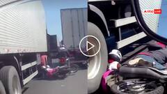 Video: इसका शनि भारी था! दो ट्रकों के बीच से निकल रहा था बाइकर, टायर के नीचे आई पीछे बैठी महिला