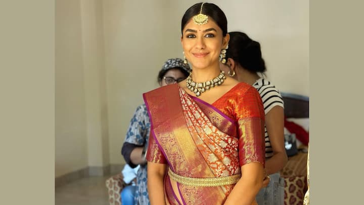 Mrunal Thakur enchants in this red silk saree with golden floral and paisley zari motifs and a contrasting purple-gold border. Paired with classic gold jewelry and subtle makeup, her look reflects timeless South Indian elegance and traditional charm. (Image Source: Instagram/ mrunalthakur)