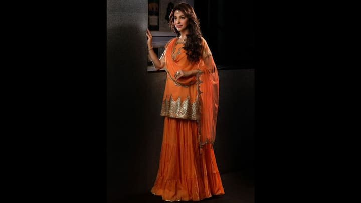 3. Vibrant Orange Sharara Set: Juhi Chawla stuns in this radiant orange sharara set that perfectly captures her graceful style. The outfit features a flowy tiered sharara paired with a short kurti adorned with intricate gold embroidery along the hemline. The matching dupatta with delicate gold borders enhances the festive appeal of the outfit. This ensemble beautifully blends traditional charm with understated glamour. Juhi’s look proves that vibrant hues, when styled with poise and minimal accessories, can create an unforgettable fashion statement. (Image Source: Instagram/@iamjuhichawla)