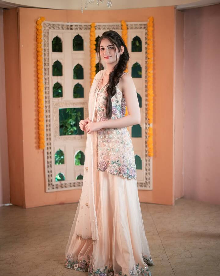 In this photo she is wearing a peach colored sharara suit. Also, to make her look more beautiful, she has done light make-up and braided her hair. His simple style is very beautiful.