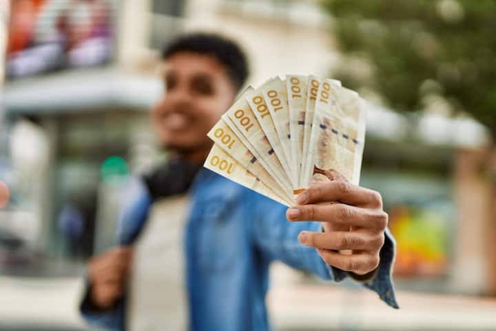 सबसे पहले बात करते हैं कुवैत की करेंसी यानी कुवैती दिनार की. यह करेंसी दुनिया की सबसे मजबूत करेंसी मानी जाती है. कुवैत की अर्थव्यवस्था तेल पर आधारित है और वहां की जनसंख्या काफी कम है. इस वजह से इस देश की करेंसी की कीमत बहुत ज्यादा रहती है. अगर कोई व्यक्ति कुवैत में नौकरी करके 50,000 कुवैती दिनार कमाता है तो भारत लौटकर यह रकम 1,44,45,718.96 रुपये हो जाती है. यानी महज 50 हजार डिनार की कमाई भारत में एक करोड़ 44 लाख रुपये से भी ज्यादा में बदल जाती है. यही वजह है कि कुवैत भारतीय युवाओं की पहली पसंद बनता जा रहा है.