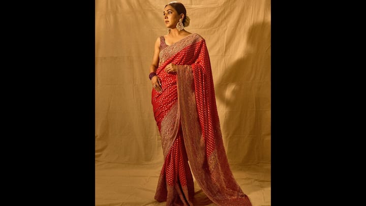 6. सदाबहार बनारसी साड़ी: नीति मोहन अपनी लुभावनी लाल बनारसी साड़ी के साथ क्लासिक भारतीय बुनाई का आकर्षण वापस लाती हैं। नाजुक बनारसी बूटी और बारीक बुने हुए पल्लू वाली गहरे लाल रंग की साड़ी में लिपटी वह हथकरघा विरासत के कालातीत आकर्षण का प्रतीक है। विस्तृत ज़री बॉर्डर के साथ जोड़े गए कपड़े की सूक्ष्म चमक उत्सव समारोहों, शादियों और सांस्कृतिक कार्यक्रमों के लिए पहनावे को एकदम सही बनाती है। उनकी स्टाइल आकर्षक होते हुए भी साधारण है। नीति ने एक अलंकृत नेकलाइन वाला स्लीवलेस ब्लाउज़ चुना है, जो साड़ी की भव्यता को प्रभावित किए बिना एक परिष्कृत समकालीन स्पर्श जोड़ता है। (छवि स्रोत: इंस्टाग्राम/@नीतिमोहन18)
