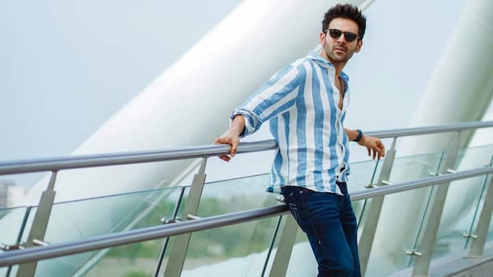 He channels coastal ease with a blue-and-white striped shirt worn slightly unbuttoned, paired with dark blue jeans. Dark sunglasses and brown boots elevate the relaxed vibe with a polished, vacation-ready finish. (Image Source: Instagram/ kartikaaryan)