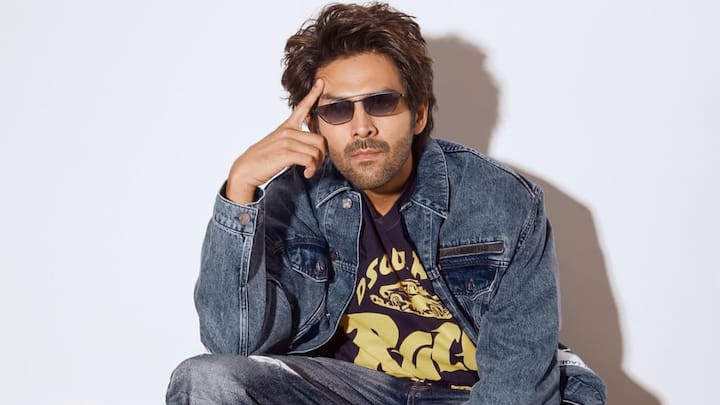 Kartik amps up rugged streetwear with this faded denim jacket, distressed jeans, and a graphic tee. Chunky paint-splattered sneakers and tinted shades add an edgy, rebellious twist to the all-denim fit. (Image Source: Instagram/ kartikaaryan)