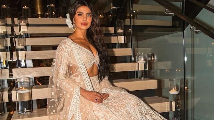 Ethereal Ivory Chikankari: Priyanka redefines subtle luxury in an ivory lehenga adorned with chikankari-style embroidery and soft sequin sheen. The plunging V-neck blouse adds a modern touch, balanced by the airy dupatta sprinkled with delicate butas. Loose waves, a fresh white flower, and statement earrings complete her serene, timeless glow. (Image Source: Instagram/ stylebyami)