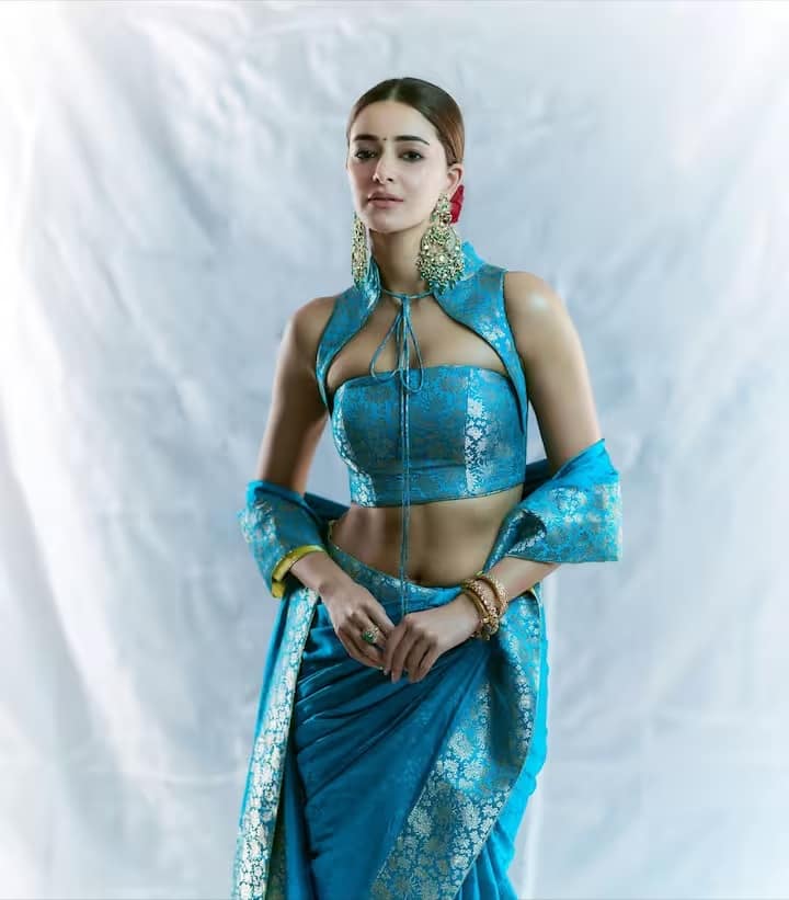 अनन्या पांडे ने यहाँ नीले रंग की बनारसी साड़ी पहनी है। इस पर सुनहरे ज़री का बारीक काम किया गया है। बारीक डिज़ाइन इस साड़ी को और भी खूबसूरत बना रहे हैं। हमेशा की तरह साड़ी पहनने की बजाय, अभिनेत्री ने पल्लू ओढ़ा है, जो उनके स्लिम फिगर को बखूबी उभार रहा है।