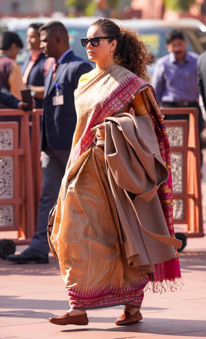 कंगना रनौत के पार्लियामेंट्री फैशन में अक्सर ट्रेडिशनल हैंडलूम साड़ियों के साथ डिज़ाइनर बैग और हल्की ज्वेलरी होती है, जो पॉलिश्ड प्रोफेशनलिज़्म और स्टाइल के बीच बैलेंस बनाती है. विंटर सेशन 2025 के पहले दिन, उन्होंने मैजेंटा बॉर्डर वाली रेडिएंट मैंगो येलो रंग की नेचुरल टसर साड़ी पहनी थी.