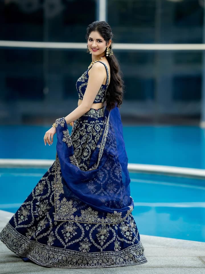 इस लुक में हर्षाली ने डीप ब्लू एम्ब्रॉयडर्ड लहंगा कैरी किया है, जो उन्हें बेहद ग्रेसफुल और रॉयल लुक दे रहा है. ओपन हेयर और मिनिमल ज्वेलरी के साथ उनका यह स्टाइलिश अंदाज़ शादी के संगीत या कॉकटेल नाइट के लिए बढ़िया ऑप्शन हो सकता है.