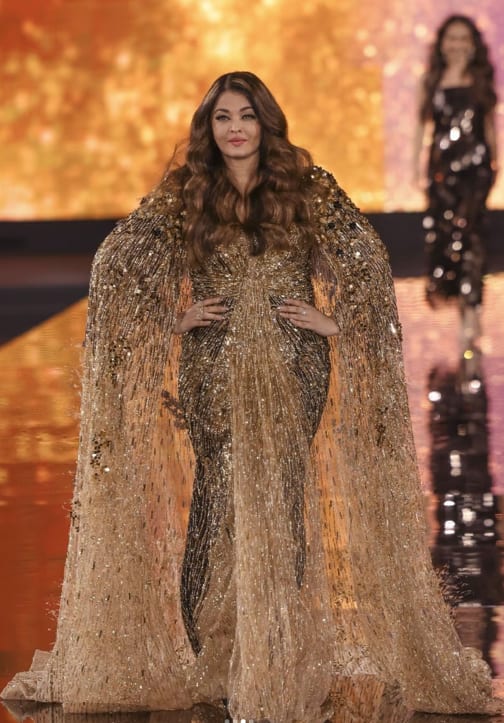 This look of the actress is quite glamorous. She is wearing a golden heavy work gown in which she is looking very beautiful. Also, the look was made even more royal by applying subtle make-up and curly hair.