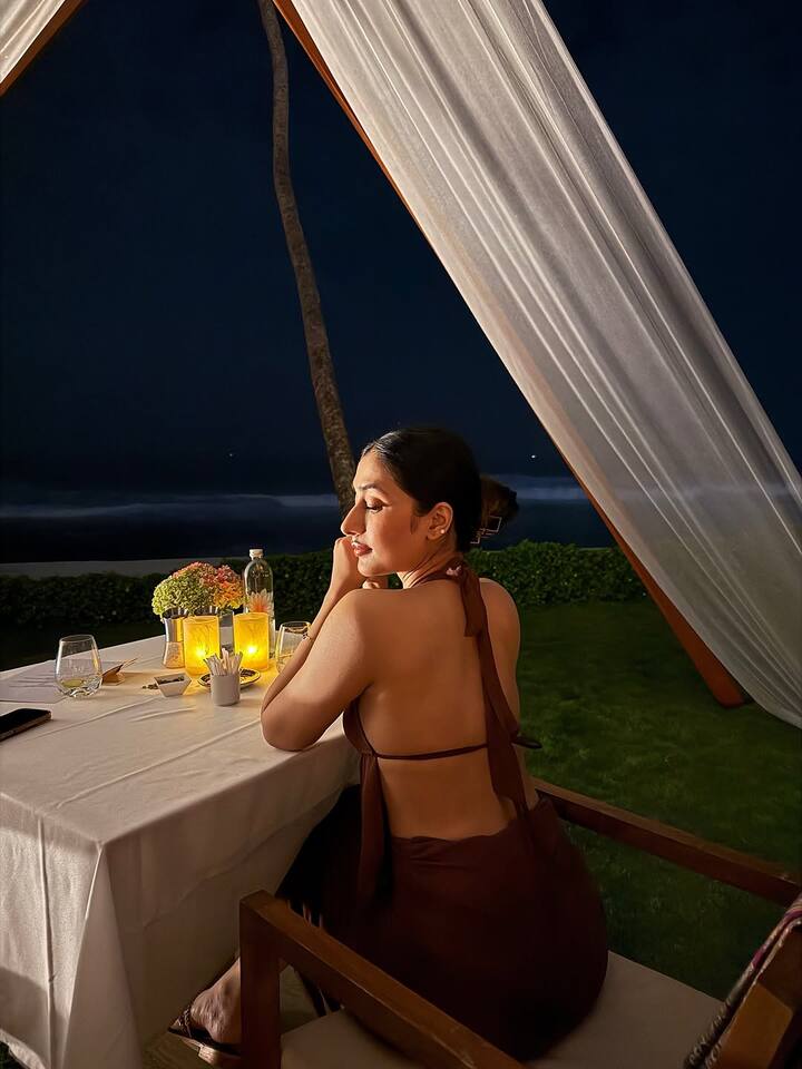 In one picture, Haseena has flaunted her backless dress very well. The actress posed in front of the camera while sitting at the dinner table on the sea shore
