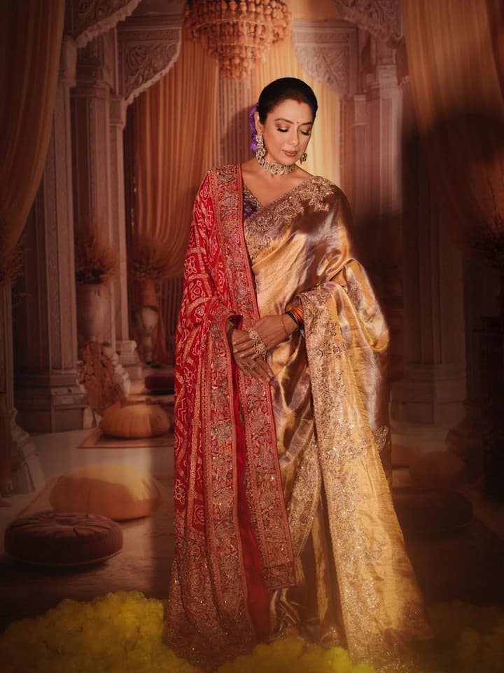 इस तस्वीरों में रूपाली बेहद ग्रेसफुल और रॉयल ट्रेडिशनल लुक में नजर आ रही हैं. उन्होंने रेड और गोल्ड टोन की खूबसूरत साड़ी पहनी है. जिस पर बारीक कढ़ाई और ट्रेडिशनल मोटिफ्स दिखाई देते हैं. साड़ी का गोल्डन बॉर्डर लुक में शाही एहसास जोड़ता है.