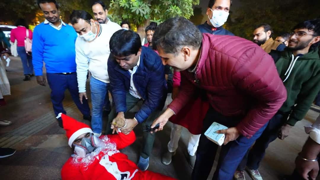 Delhi pollution Santa Claus wears mask and distributes toffees with AAP leaders in Connaught Place दिल्ली के प्रदूषण से सेंटा क्लॉज हुए बीमार, मास्क पहन AAP नेताओं संग कनॉट प्लेस में बांटी टॉफी