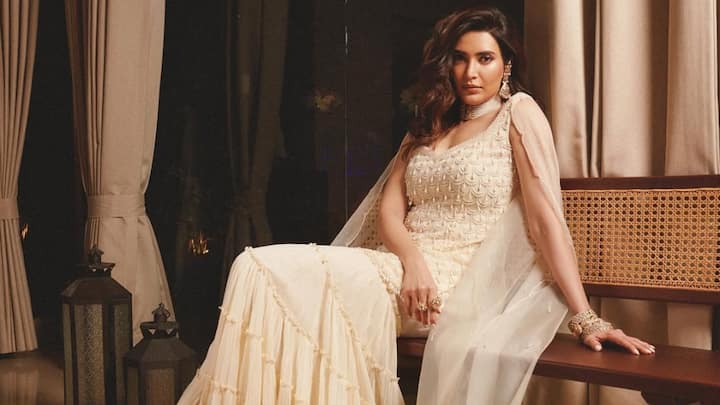 Ivory Elegance: Draped in this soft ivory ensemble, Karishma exudes understated royalty with a delicately embroidered bodice and a gently flared tiered skirt. The sheer dupatta enhances the romantic silhouette, lending the look a serene, ethereal glow. (Image Source: Instagram/ karishmaktanna)