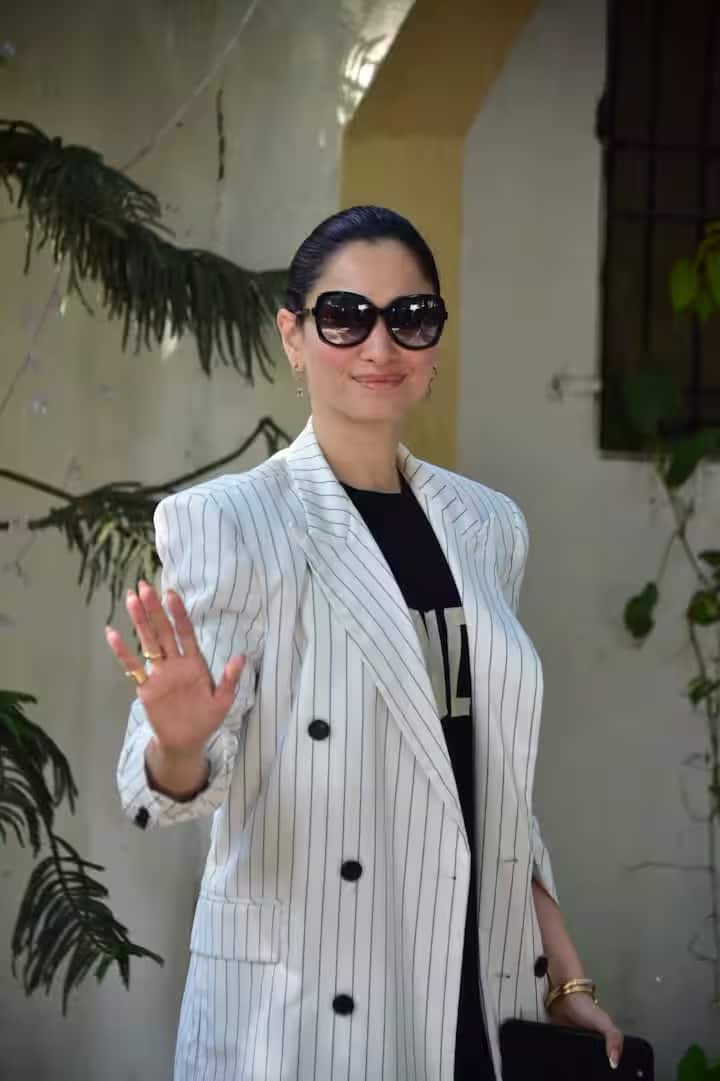 इस ड्रेस के ऊपर उन्होंने सफेद और काले रंग की धारीदार ब्लेज़र पहनी है, जो पूरे पहनावे को एक परफेक्ट फॉर्मल लुक देती है।