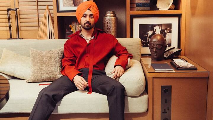 Anchored by a bold saffron turban, Diljit pairs a deep red silk kurta-style shirt with tailored black trousers for a refined high–low contrast. Minimal jewellery and a relaxed stance keep the look rooted, confident, and quietly powerful. (Image Source: Instagram/ diljitdosanjh)