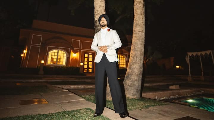 An ivory tuxedo jacket with satin lapels meets fluid black trousers, blending old-world elegance with modern ease. The black turban and a single red buttonhole add cultural depth and cinematic restraint. (Image Source: Instagram/ diljitdosanjh)