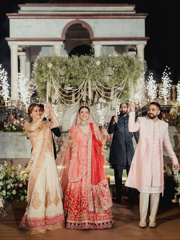 In one of the photos, Kriti walked alongside Nupur under the phoolon ki chadar as she made her way down the aisle.