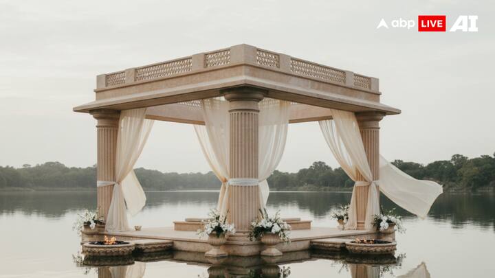 7. By-the-Water Mandaps - Floating Ceremonial Architecture: Floating mandaps redefine wedding architecture by placing the ceremony directly on water. Supported by sculptural pillars and layered canopies, these mandaps appear to hover over lakes or pools. Reflections of light, florals, fire elements, and flowing drapes create a dreamlike, immersive atmosphere, turning nature itself into a design element. (Image Source: ABP Live AI)