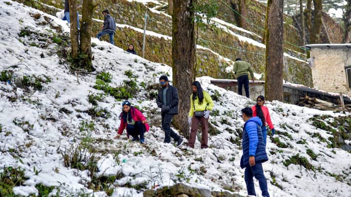 Tourists walk carefully along a snow-covered hillside in Mussoorie, as the Queen of Hills experiences fresh snowfall, boosting winter tourism while affecting road conditions. (Image Source: PTI)