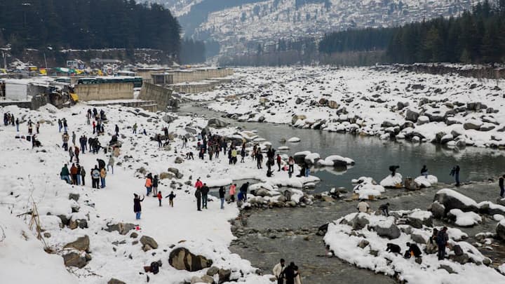 Visitors gather in a snow-covered valley near the Beas River in Manali, where fresh snowfall has turned the region into a major winter attraction for tourists. (Image Source: PTI)