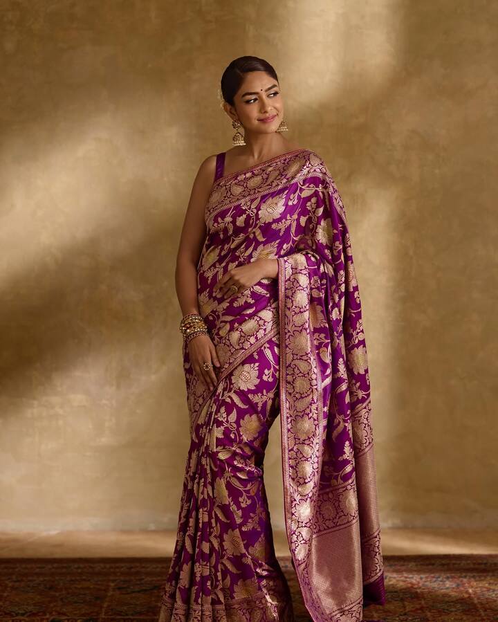 Mrunal Thakur is looking very beautiful in this purple colored Kanjeevaram saree. She has worn a free palla in which she is looking quite modern. You can complete this look with simple accessories and a bun.