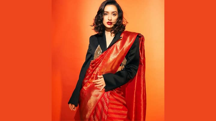 Saree Styled With A Blazer: Redefining ethnic glamour, she pairs a luxurious red silk saree with a tailored black blazer. Bold lipstick and a chic wavy bob give the look a powerful, contemporary edge. It’s regal dressing with an editorial statement. (Image Source: Instagram/ shraddhakapoor)