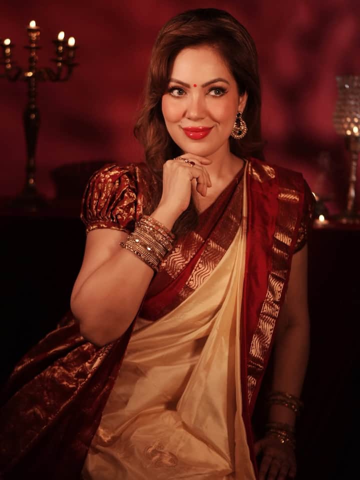 Her blouse is of red and golden design, which is shining. This blouse with puff sleeves gives her a classic and royal touch.