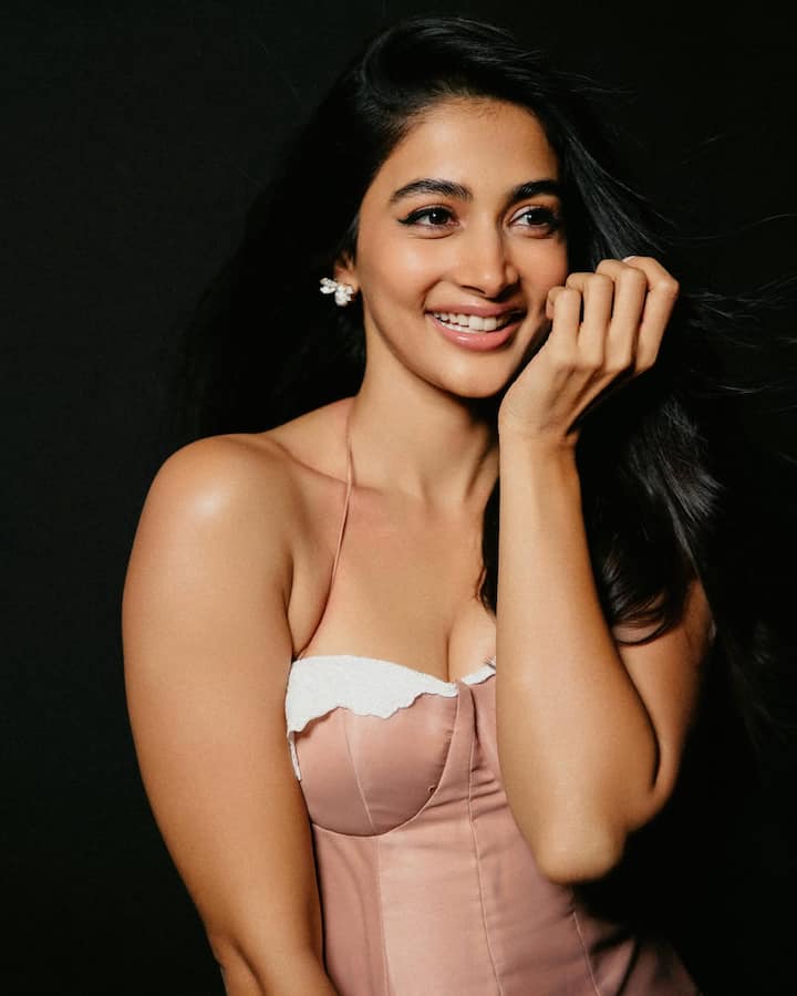 Pooja Hegde is wearing a baby pink colored flowy midi dress, which is looking elegant. The fabric of the dress is making the whole look very graceful and dreamy.